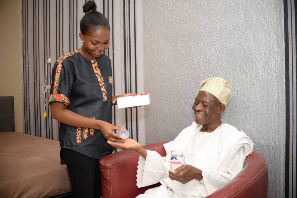 Nigerian healthcare worker providing compassionate care to elderly patient